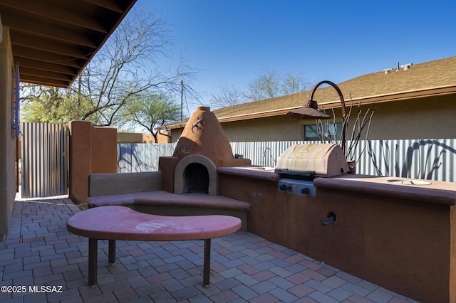 view of patio / terrace featuring a fireplace, area for grilling, and fence