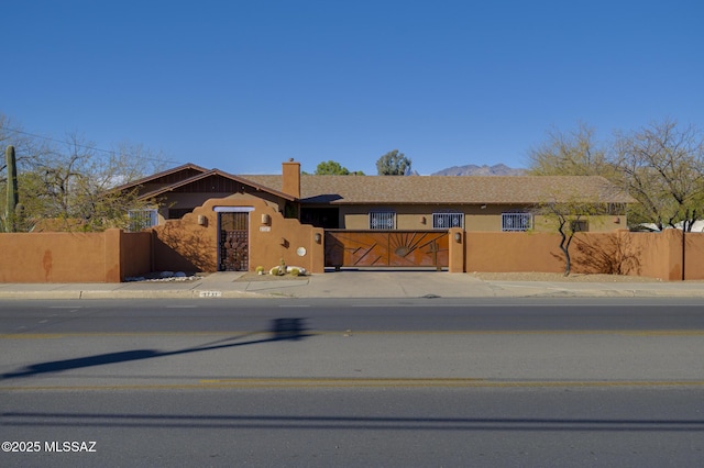 ranch-style house with a fenced front yard, driveway, stucco siding, and a gate