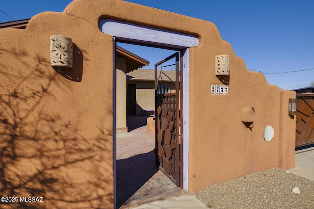 exterior space with a gate, fence, and stucco siding