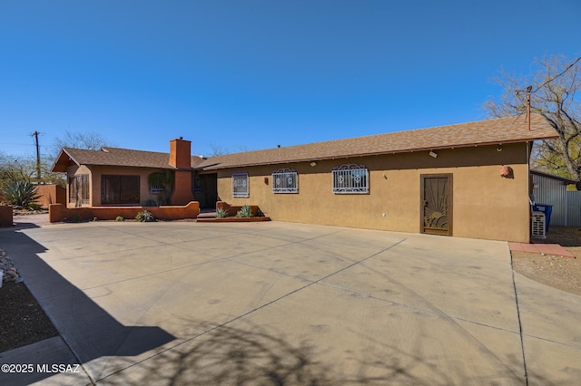 back of house featuring stucco siding and a chimney