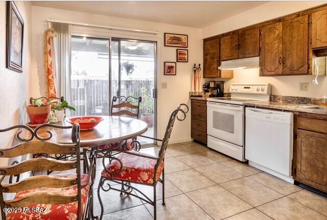 35 E Pastime Rd, Tucson, AZ 85705 - kitchen with white appliances, light tile patterned floors, brown cabinets, under cabinet range hood, and a sink