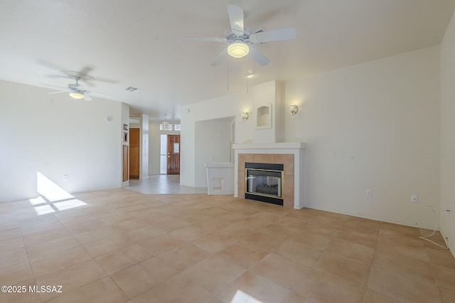 unfurnished living room featuring ceiling fan, light tile patterned floors, a tiled fireplace, and visible vents