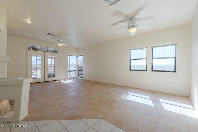 spare room featuring light tile patterned floors, ceiling fan, visible vents, and french doors