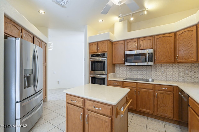 kitchen featuring appliances with stainless steel finishes, brown cabinetry, and tasteful backsplash