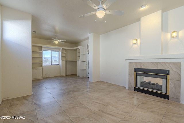 unfurnished living room featuring a ceiling fan and a tiled fireplace