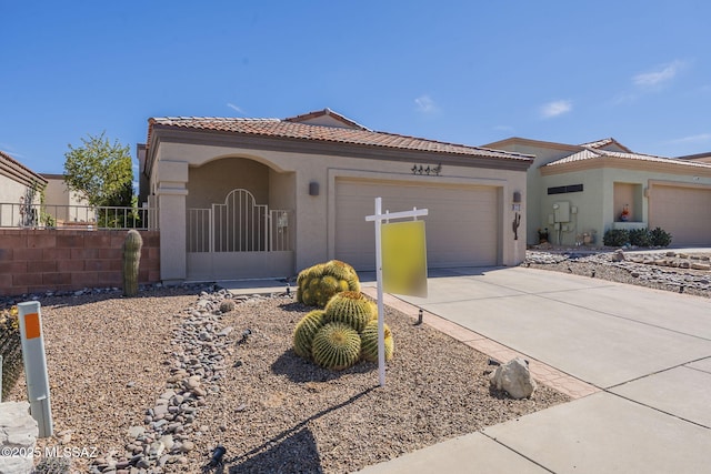 mediterranean / spanish-style home with an attached garage, fence, driveway, a tiled roof, and stucco siding