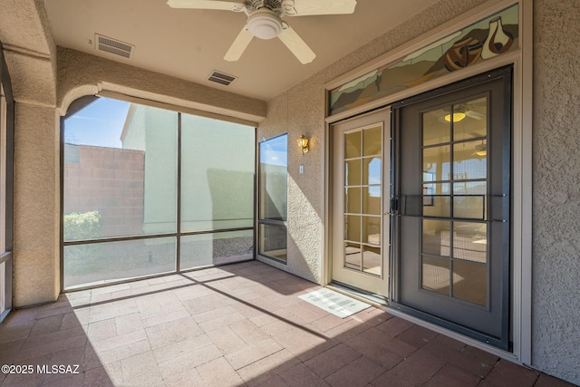 unfurnished sunroom with a ceiling fan and visible vents