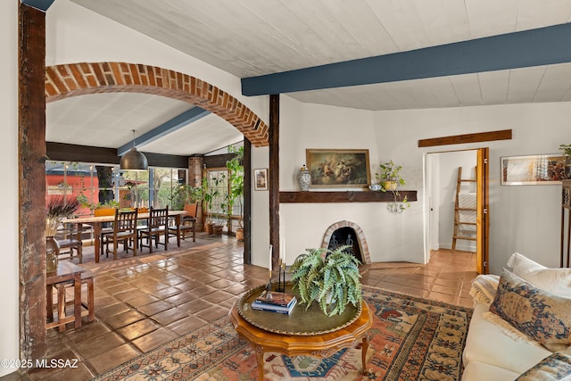 living room with lofted ceiling with beams, a fireplace, arched walkways, and tile patterned floors