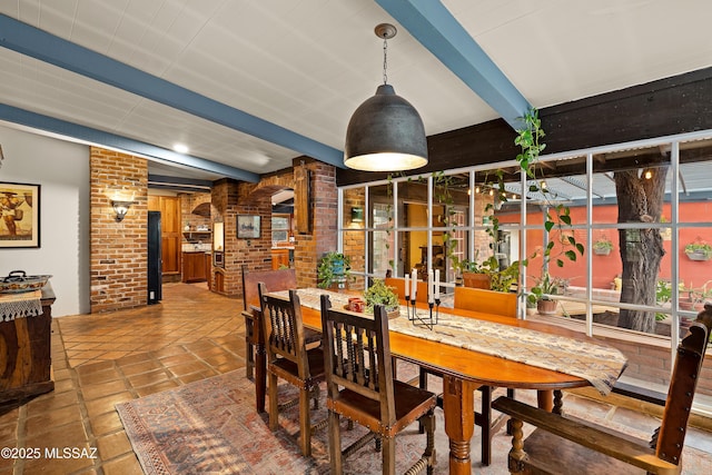 dining room with beam ceiling and brick wall