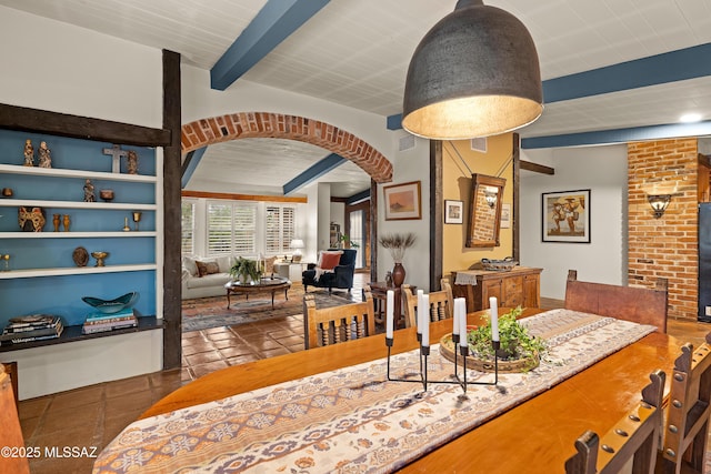 tiled dining area featuring arched walkways, visible vents, and beam ceiling