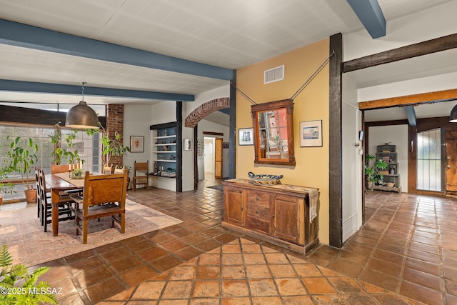 dining space featuring arched walkways, beam ceiling, stone tile flooring, and visible vents