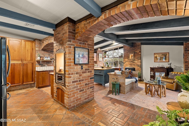 kitchen featuring vaulted ceiling with beams, light countertops, visible vents, and freestanding refrigerator