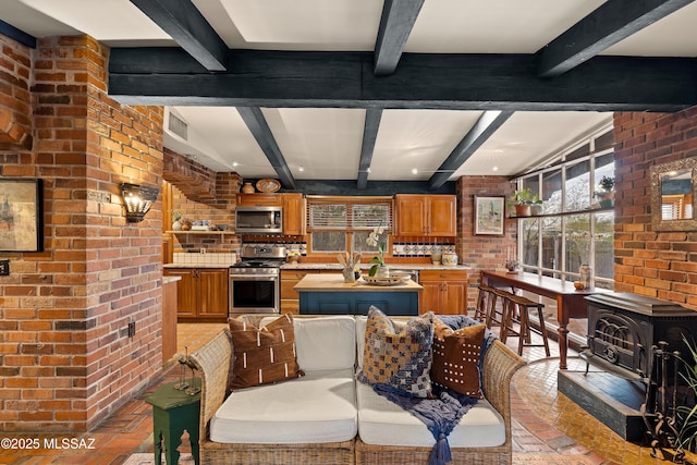 kitchen featuring brown cabinetry, brick wall, a wood stove, brick floor, and stainless steel appliances