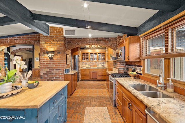 kitchen with stainless steel appliances, butcher block counters, a sink, and beam ceiling