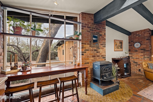 dining room with brick floor, a wood stove, vaulted ceiling with beams, and a wall of windows