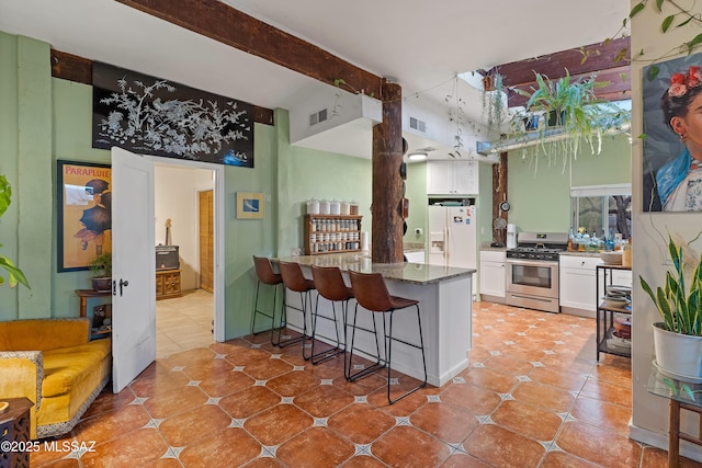 kitchen featuring white fridge with ice dispenser, stainless steel gas range, visible vents, and white cabinets