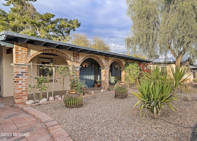 view of front of home featuring brick siding and stucco siding