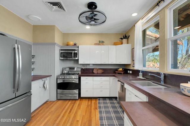 kitchen featuring stainless steel appliances, visible vents, light wood-style flooring, and white cabinetry