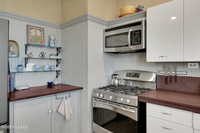 kitchen with stainless steel appliances, wooden counters, and white cabinets