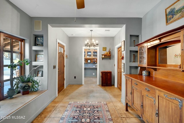 interior space featuring ceiling fan with notable chandelier, light tile patterned flooring, and baseboards