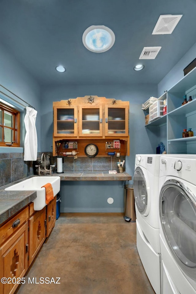 laundry room featuring cabinet space, independent washer and dryer, a sink, and visible vents