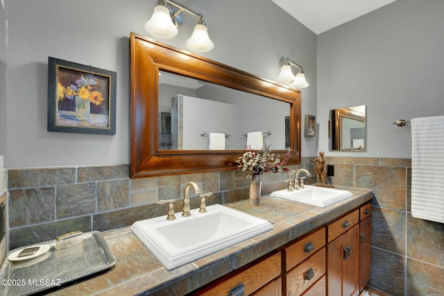 full bath with a sink, tile walls, and double vanity