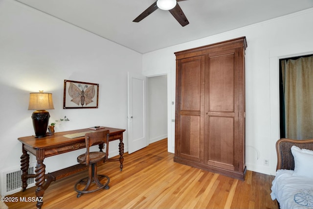 home office with light wood-type flooring, visible vents, and a ceiling fan