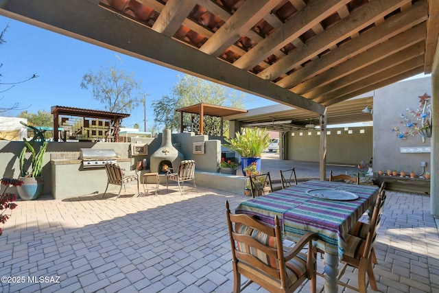 view of patio with a warm lit fireplace and area for grilling