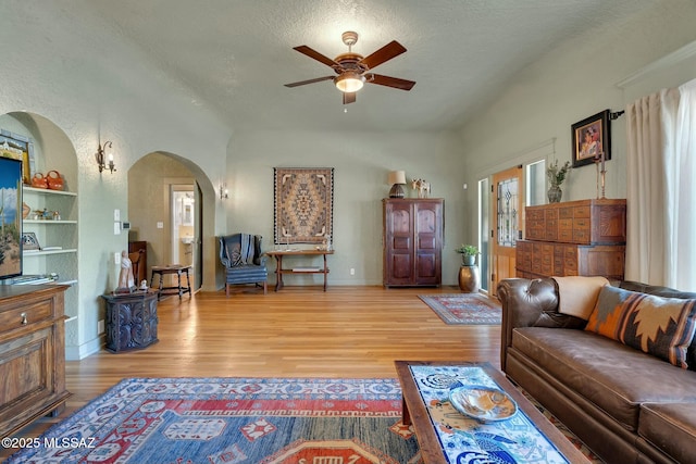 living room with arched walkways, ceiling fan, a textured ceiling, and wood finished floors