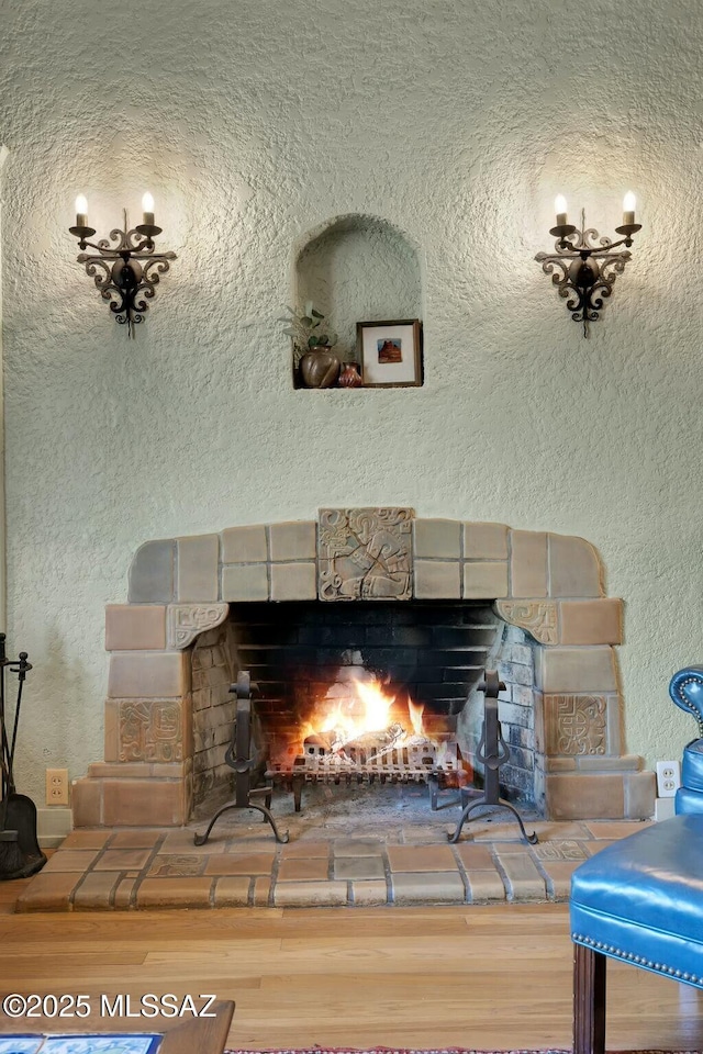 interior details featuring a fireplace, wood finished floors, and a textured wall