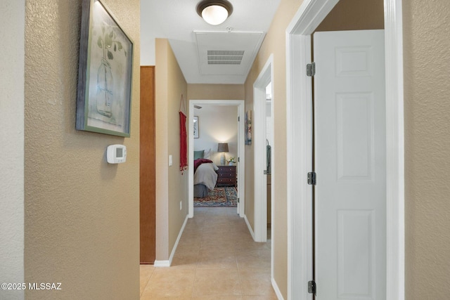 corridor featuring light tile patterned floors, visible vents, and baseboards