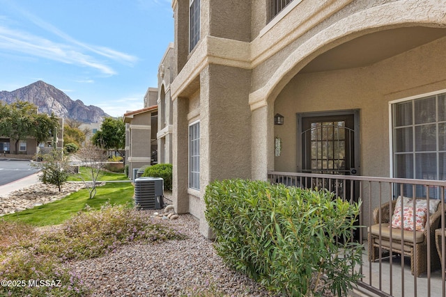 property entrance with stucco siding, a mountain view, and central AC unit