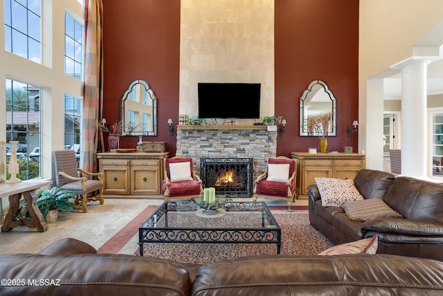 living room featuring a high ceiling, a fireplace, and decorative columns