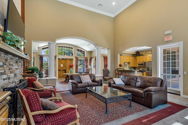 living room featuring ornate columns, visible vents, a high ceiling, and ornamental molding