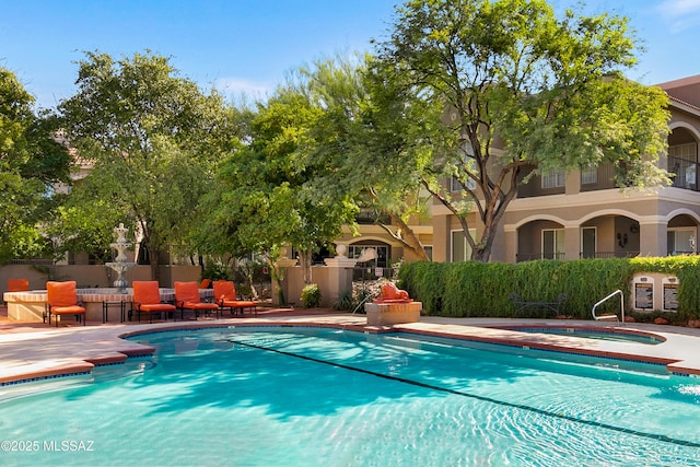 pool featuring a patio area, a hot tub, and fence