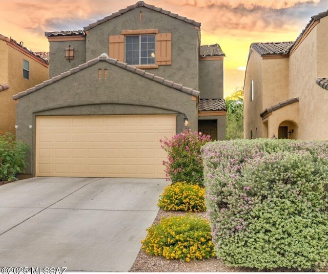 mediterranean / spanish home featuring driveway, a tile roof, and stucco siding