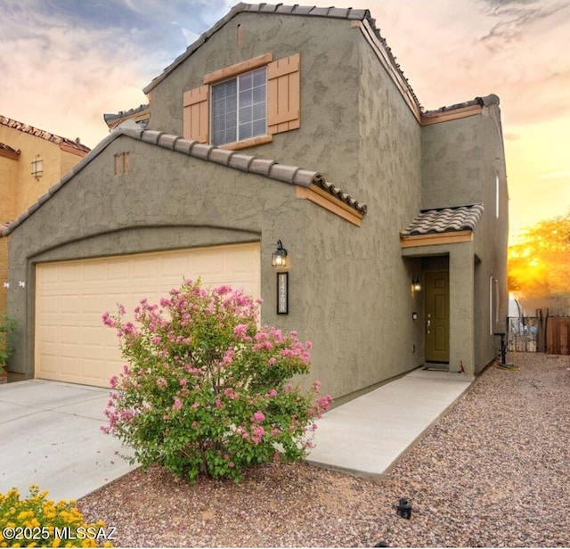 view of front of house featuring a garage, a tiled roof, and stucco siding