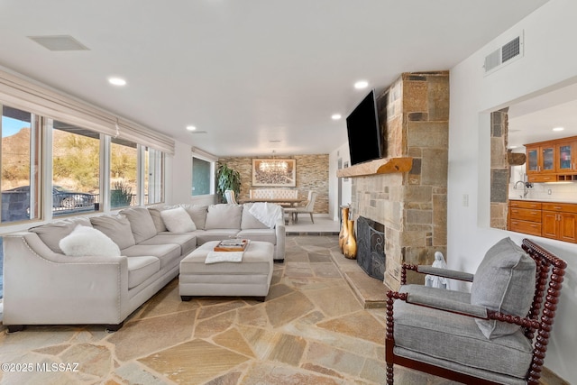 living room featuring visible vents, stone flooring, a fireplace, a chandelier, and recessed lighting