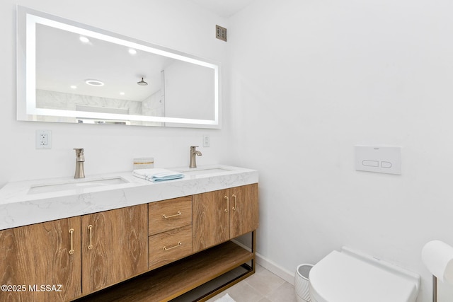 full bathroom featuring double vanity, a sink, toilet, and baseboards