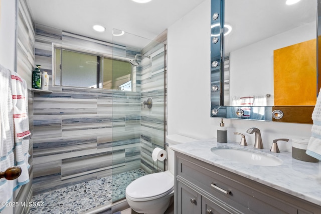 bathroom featuring a shower stall, toilet, and vanity