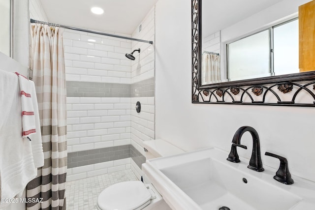 bathroom featuring a sink, a tile shower, and toilet