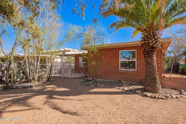 view of front of home featuring brick siding, a patio area, and fence