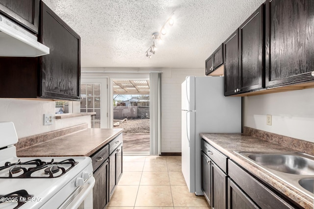 kitchen featuring ventilation hood, light tile patterned floors, a sink, white appliances, and a textured ceiling