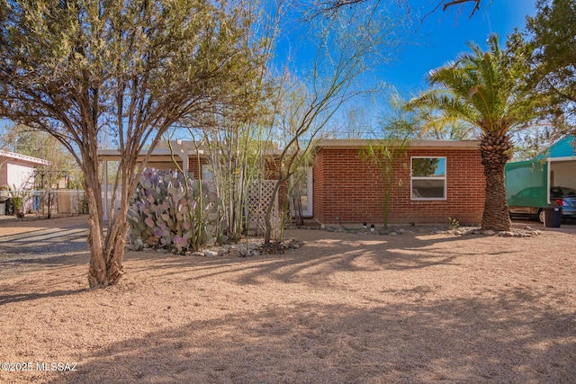 back of house with brick siding and fence