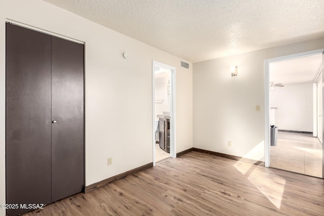 unfurnished bedroom with visible vents, a closet, baseboards, light wood-style flooring, and a textured ceiling
