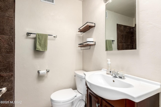 bathroom with toilet, vanity, and visible vents