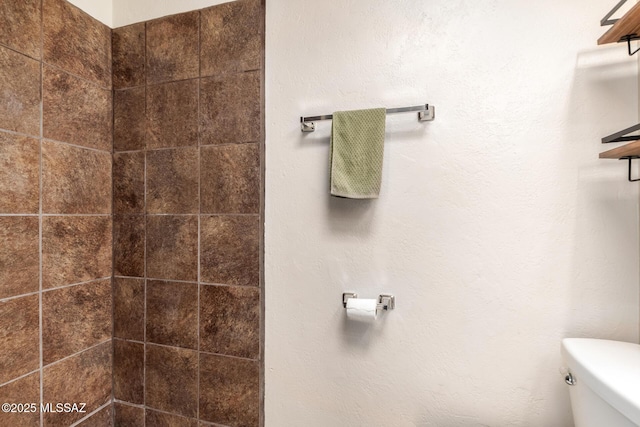 bathroom with tiled shower and toilet