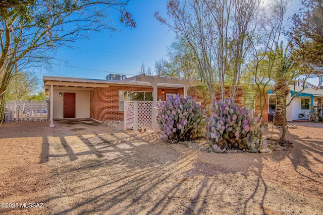 ranch-style home featuring brick siding and fence