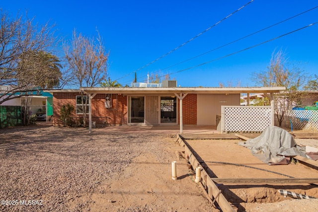 rear view of property with brick siding, fence, and a patio area