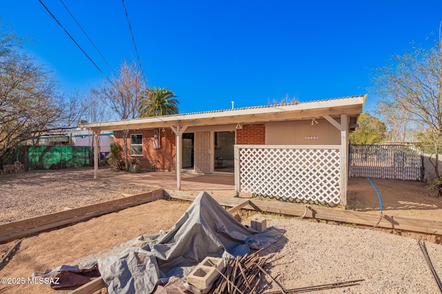rear view of house featuring brick siding and fence